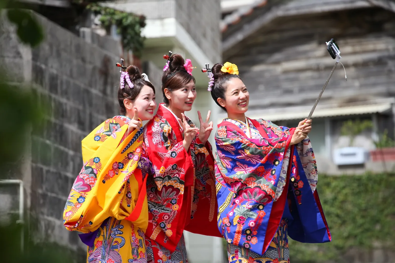琉装姿の女性3人が自撮り棒でセルフィーを撮る様子