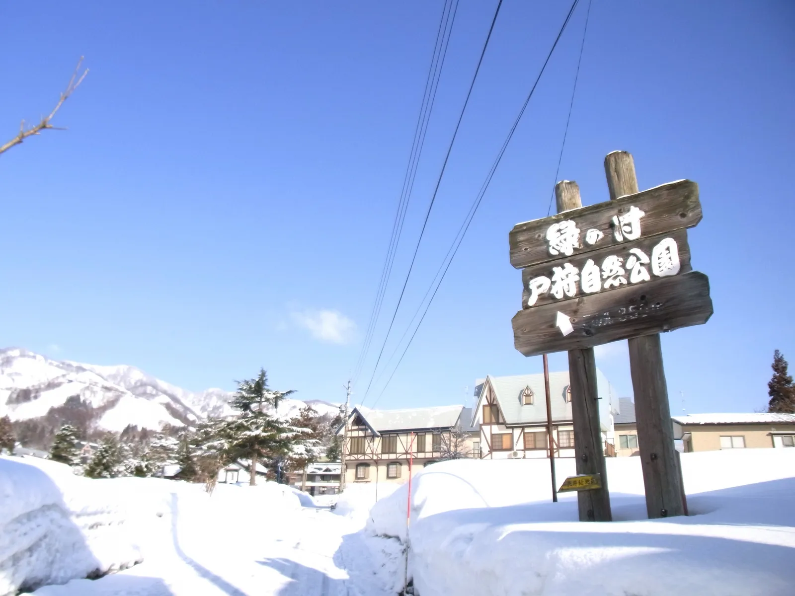 「戸狩自然公園」と書かれた木製の案内看板と、周辺の雪景色