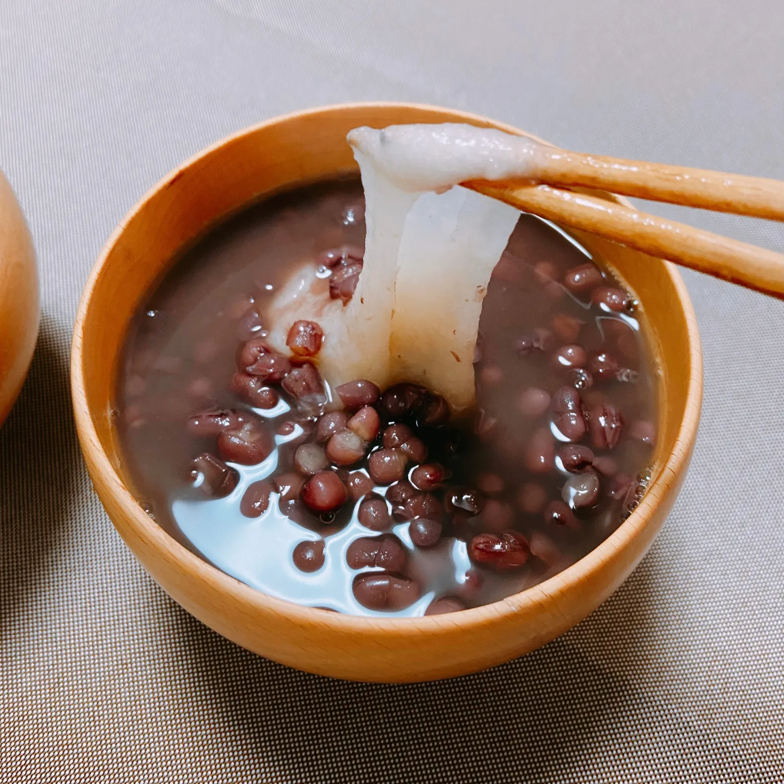 小豆の入ったぜんざいから、箸で白い餅を持ち上げる様子