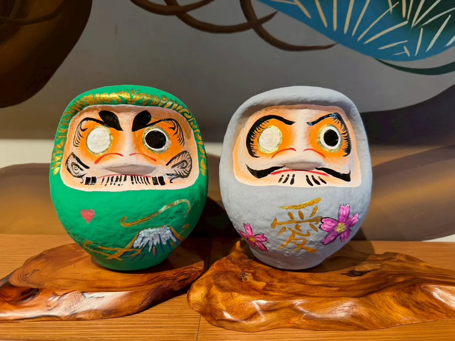 緑色のだるまと白色のだるまが木の台に並ぶ完成品