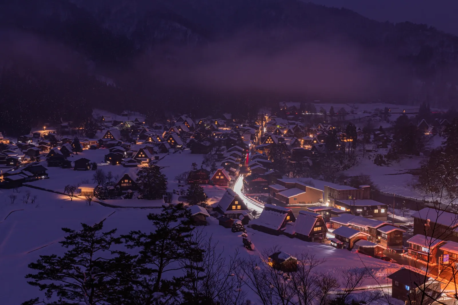 雪に覆われた白川郷の合掌造り集落と、家々の灯りを高台から眺めた夜景