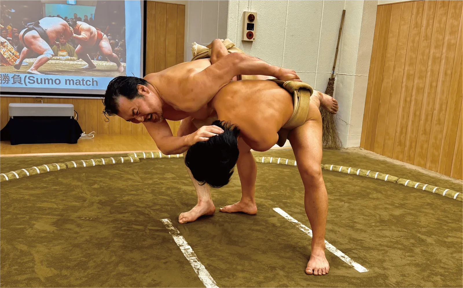 Two former wrestlers grappling and moving into a throw in the ring