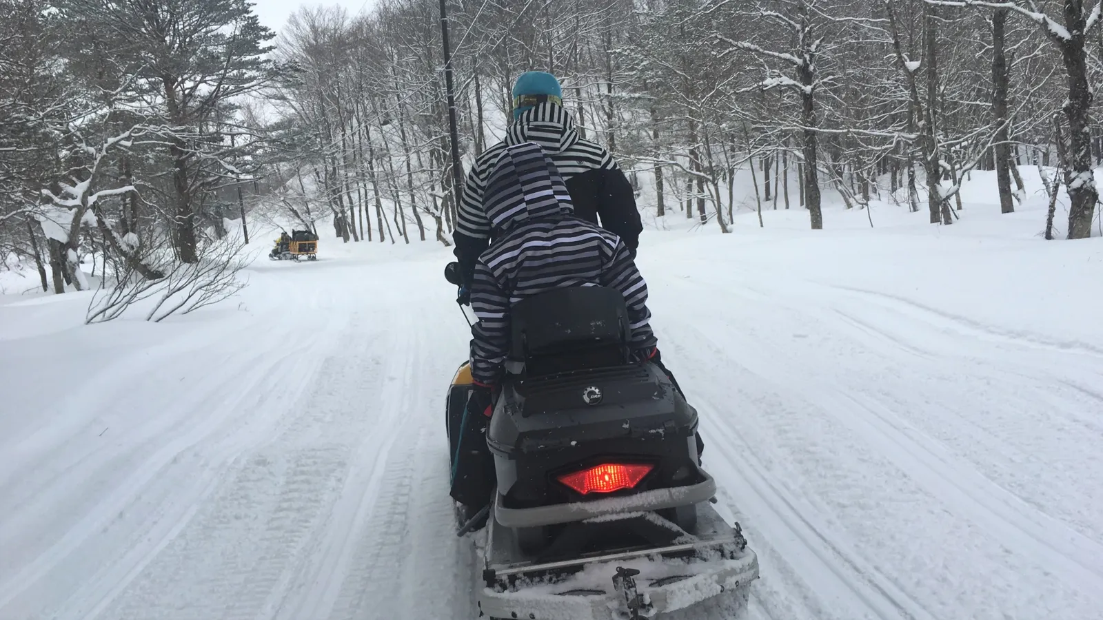 北海道の雪景色を駆け抜けるスノーモービルのイメージ
