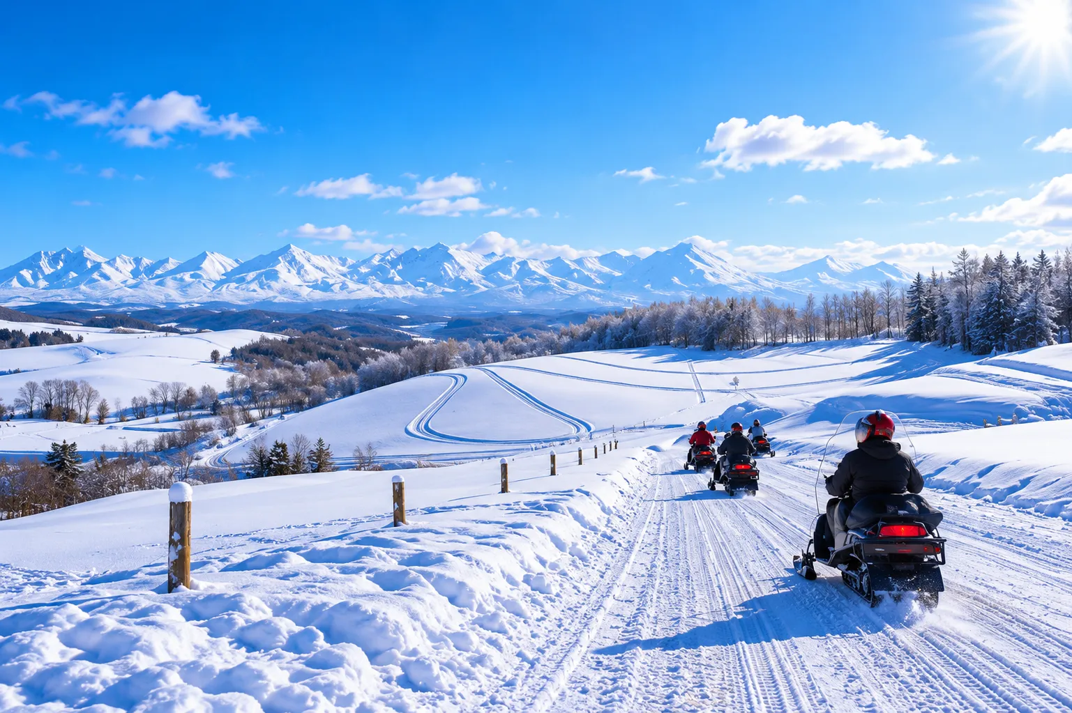A line of snowmobiles riding through snowy hills with mountains behind