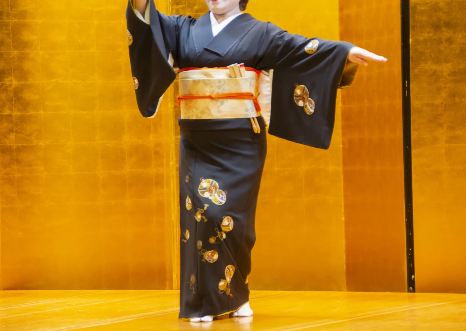 金屏風の前で両腕を広げて日本舞踊を踊る様子