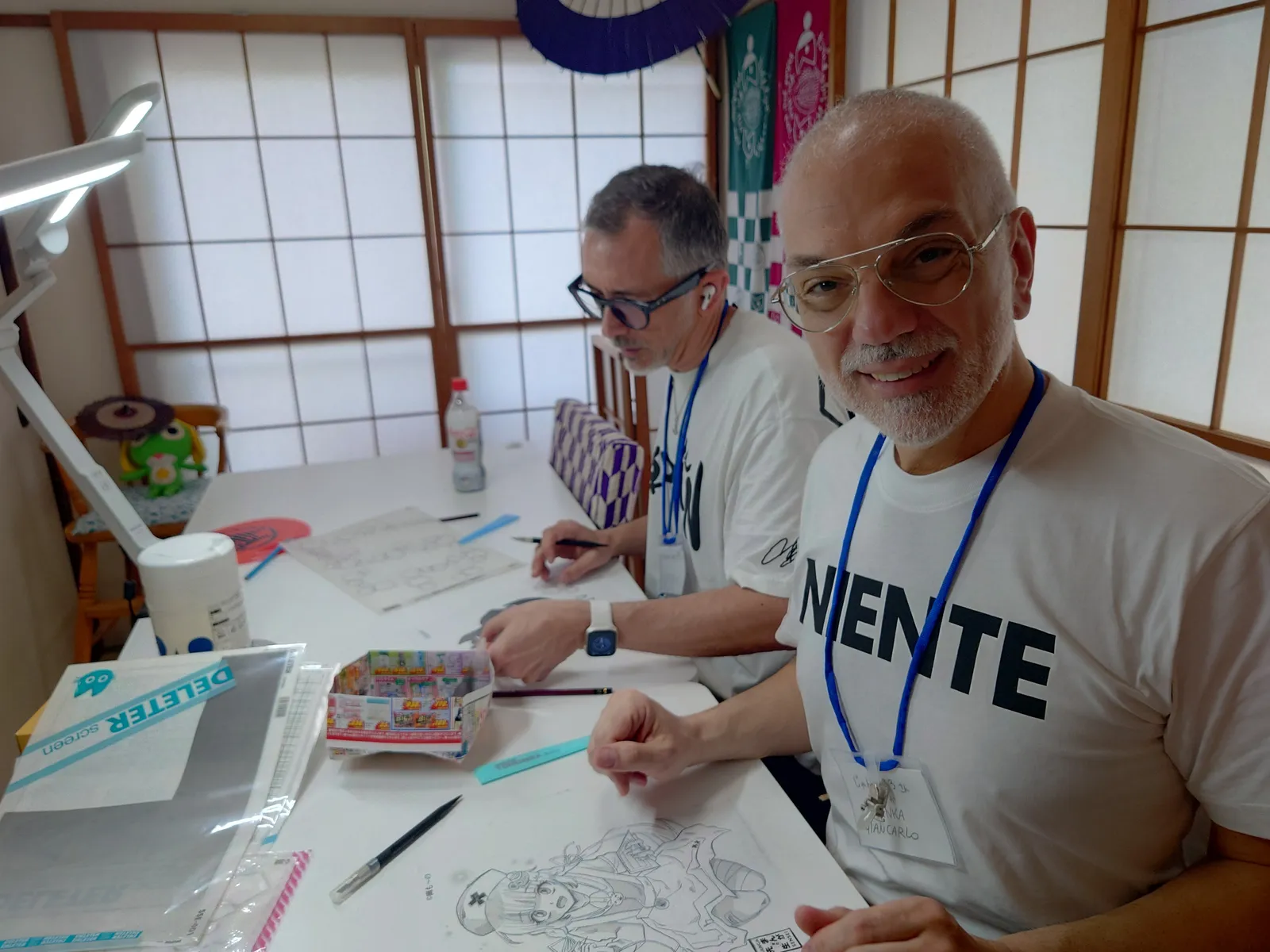 障子の前で作品を掲げる参加者たち