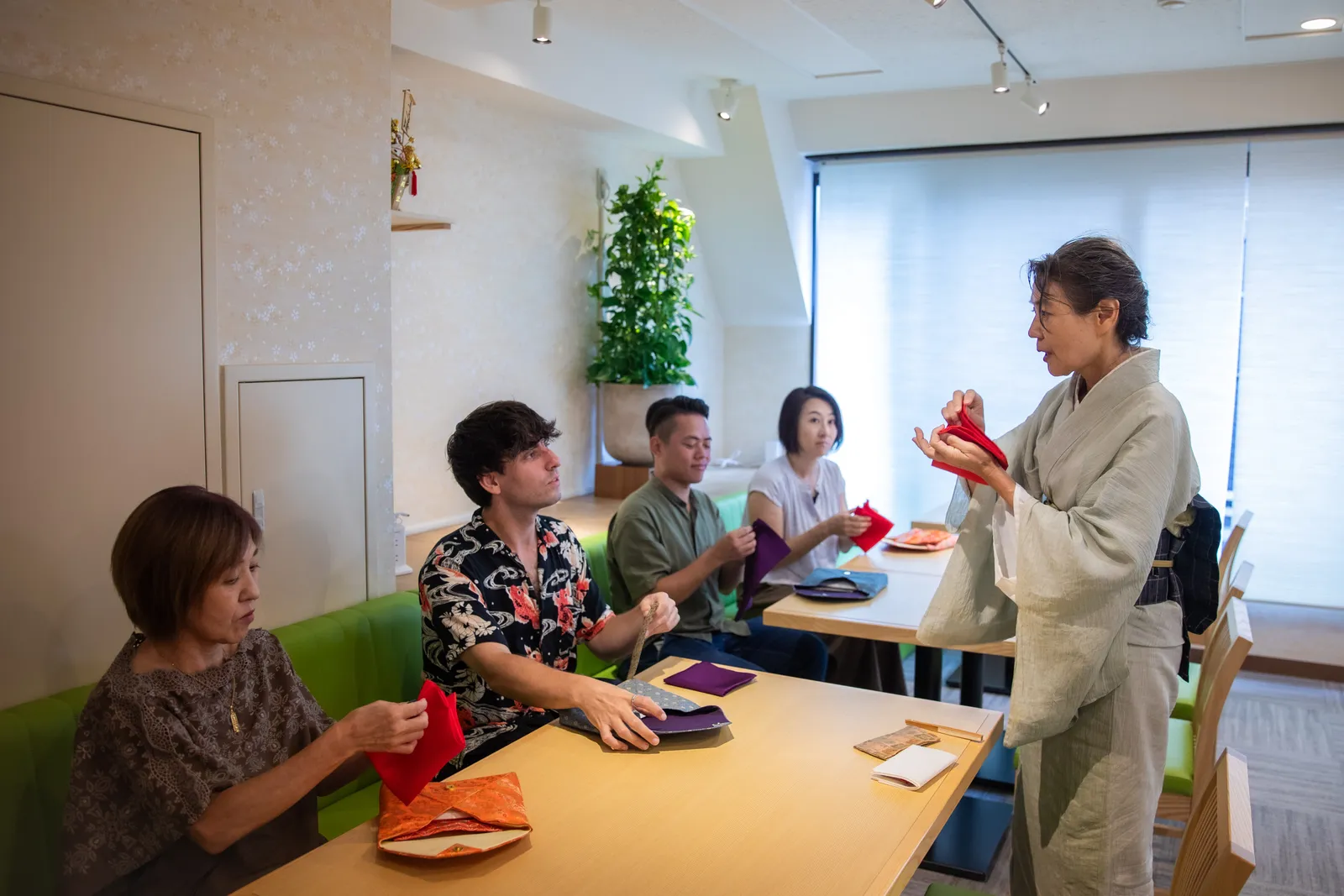 講師の手本を見ながら赤や紫の袱紗を扱う参加者