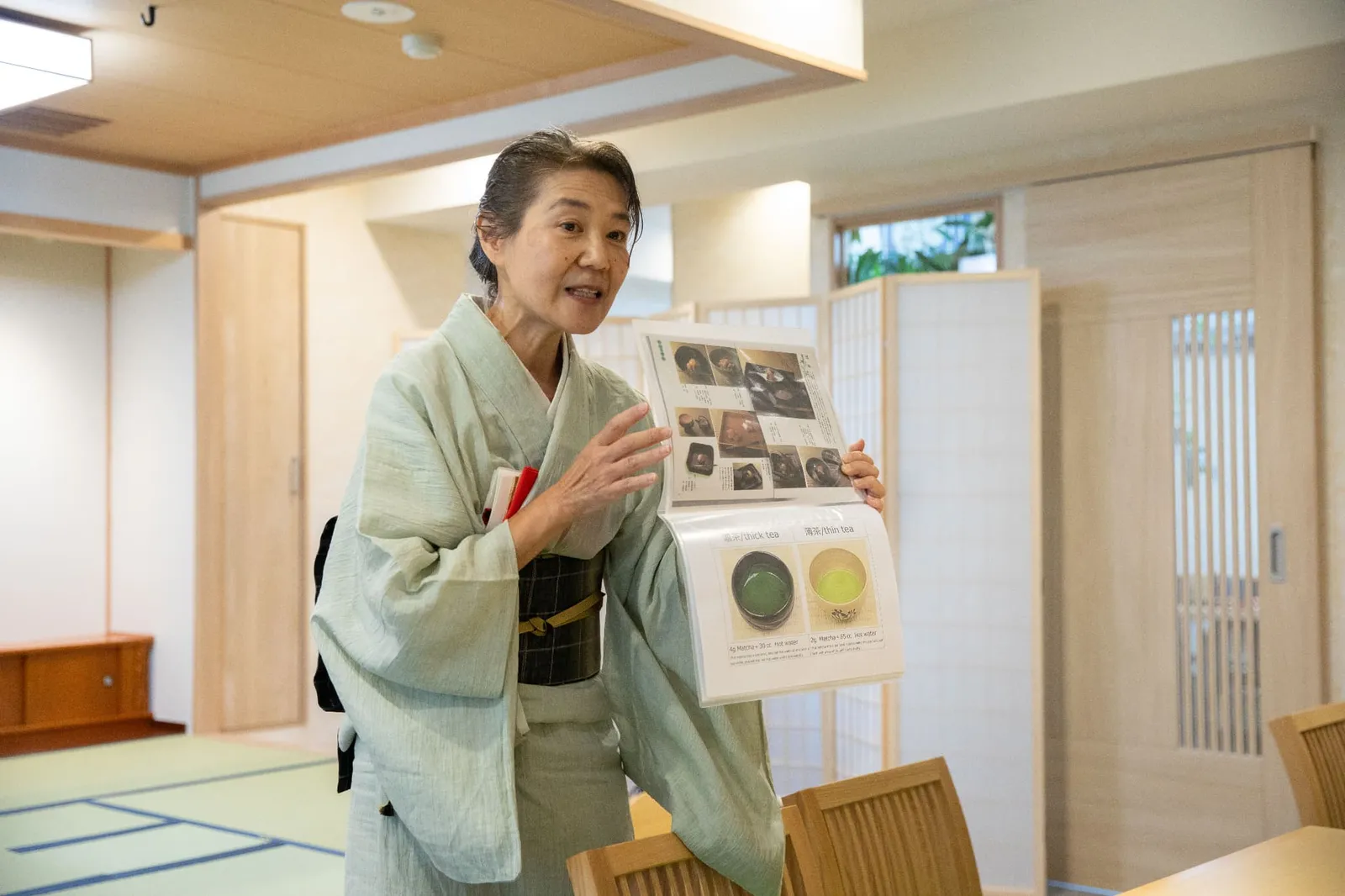 写真入りの資料を手に、参加者に説明する着物姿の講師