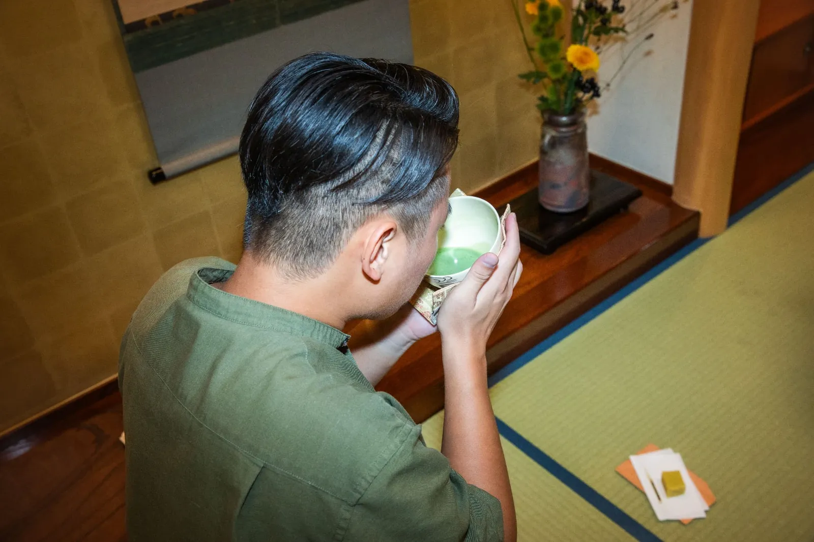 床の間の前で茶碗を両手で持ち抹茶を飲む参加者