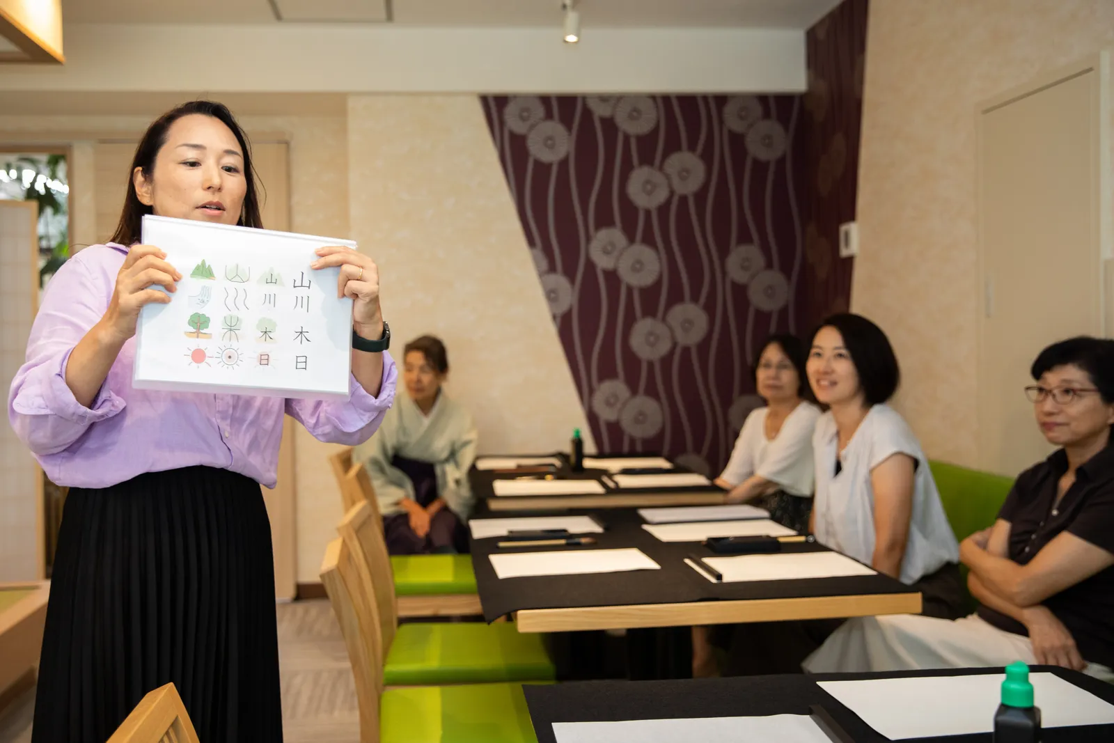 An instructor explaining the origins of kanji with diagrams to participants