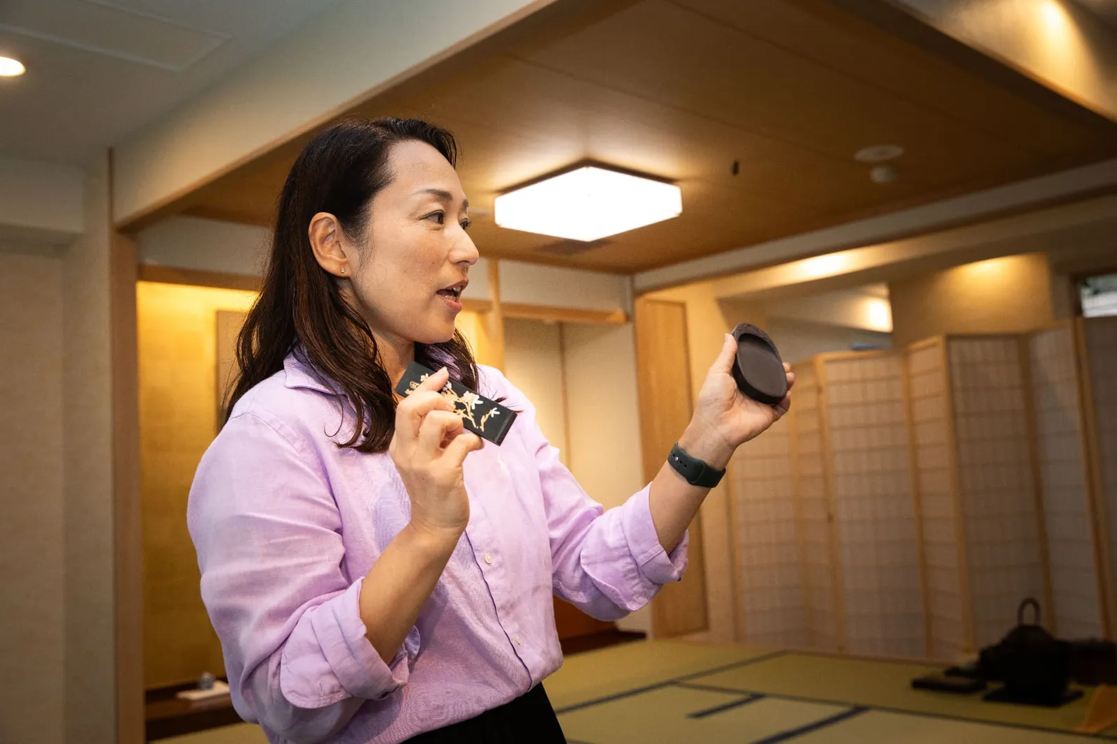 An instructor explaining while holding an ink stick and inkstone