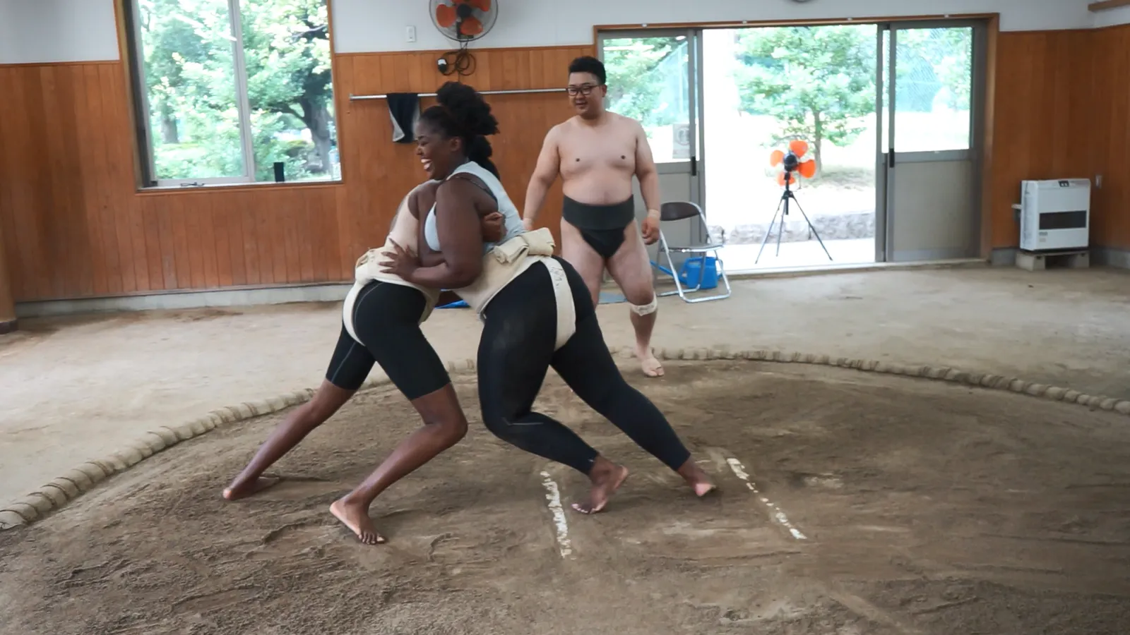 A participant in a mawashi grappling with the rikishi on the ring