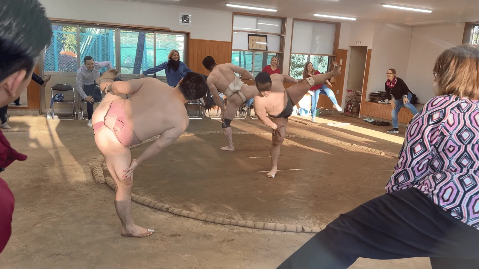 The rikishi and participants practicing shiko together around the ring