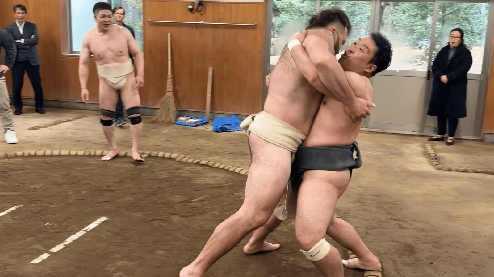 A participant locking arms head-on with the rikishi