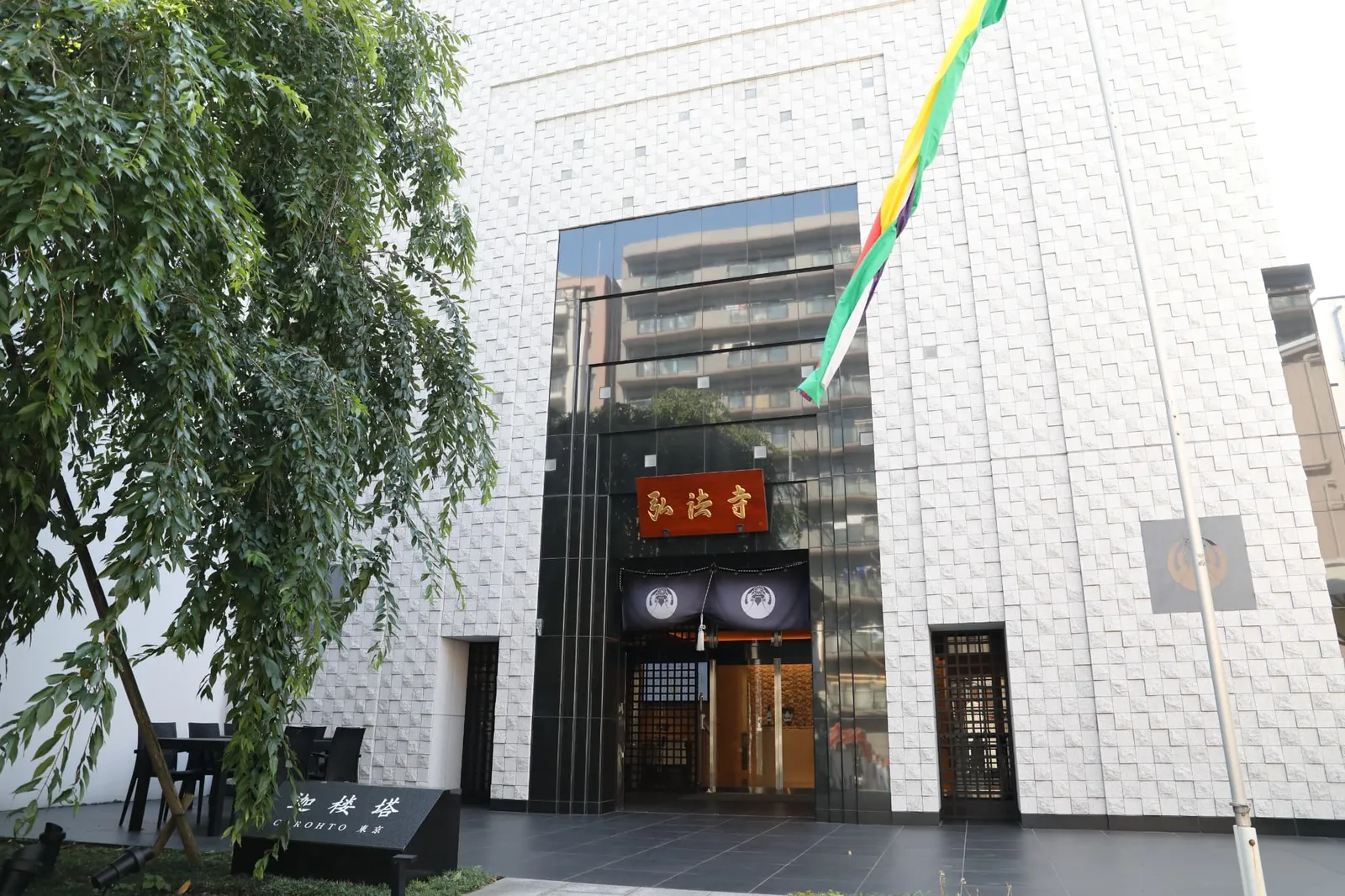 白い石壁に「弘法寺」の扁額と紺の暖簾が掛かる寺院の入口