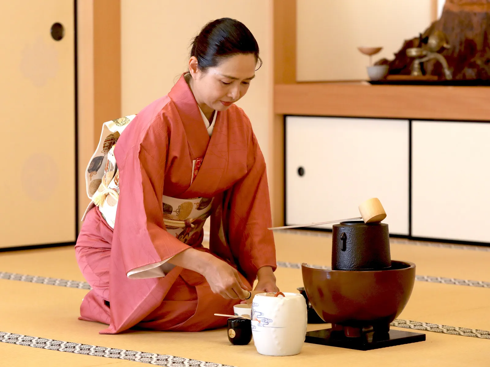 着物姿の女性が畳の上で茶道具を扱う様子