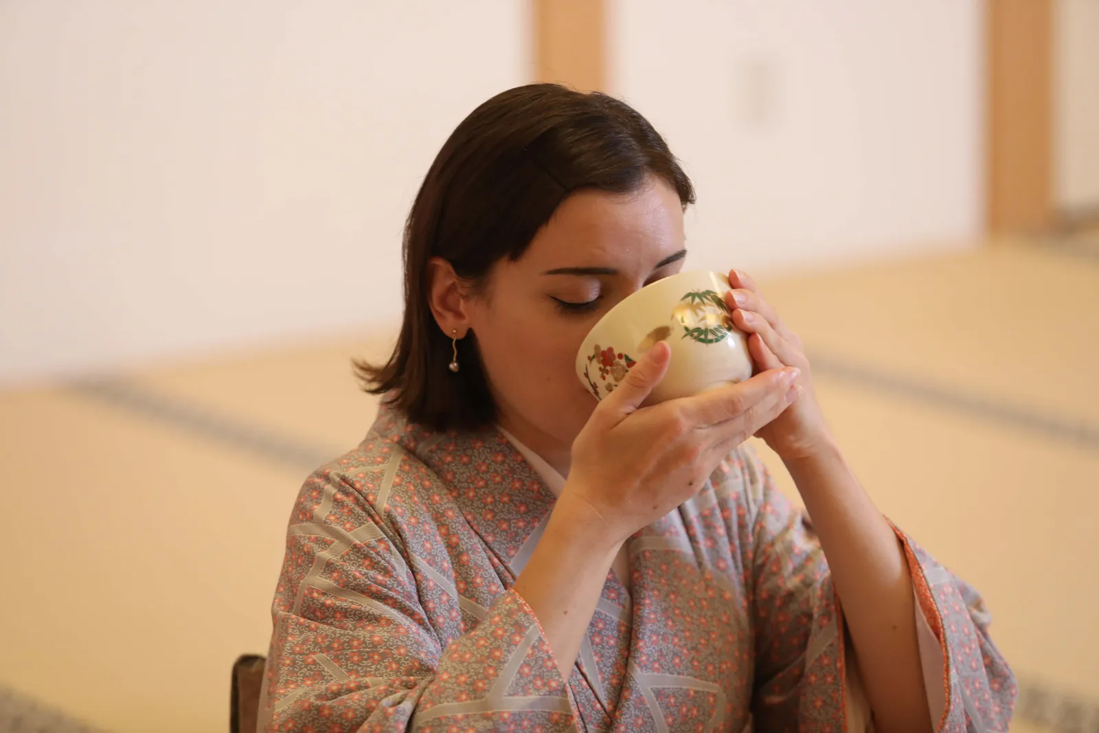 着物姿の参加者が両手で茶碗を持ち抹茶を飲む様子