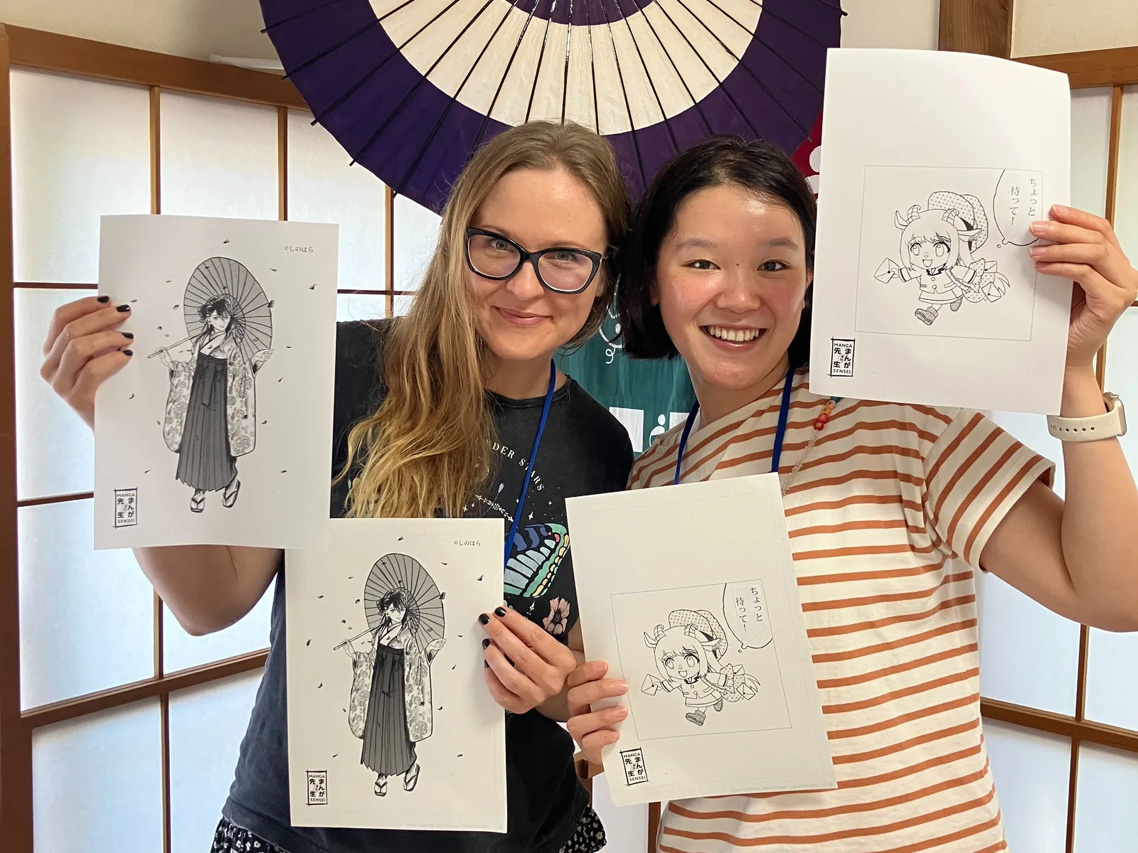講師と子どもたちが完成したイラストを掲げる集合写真