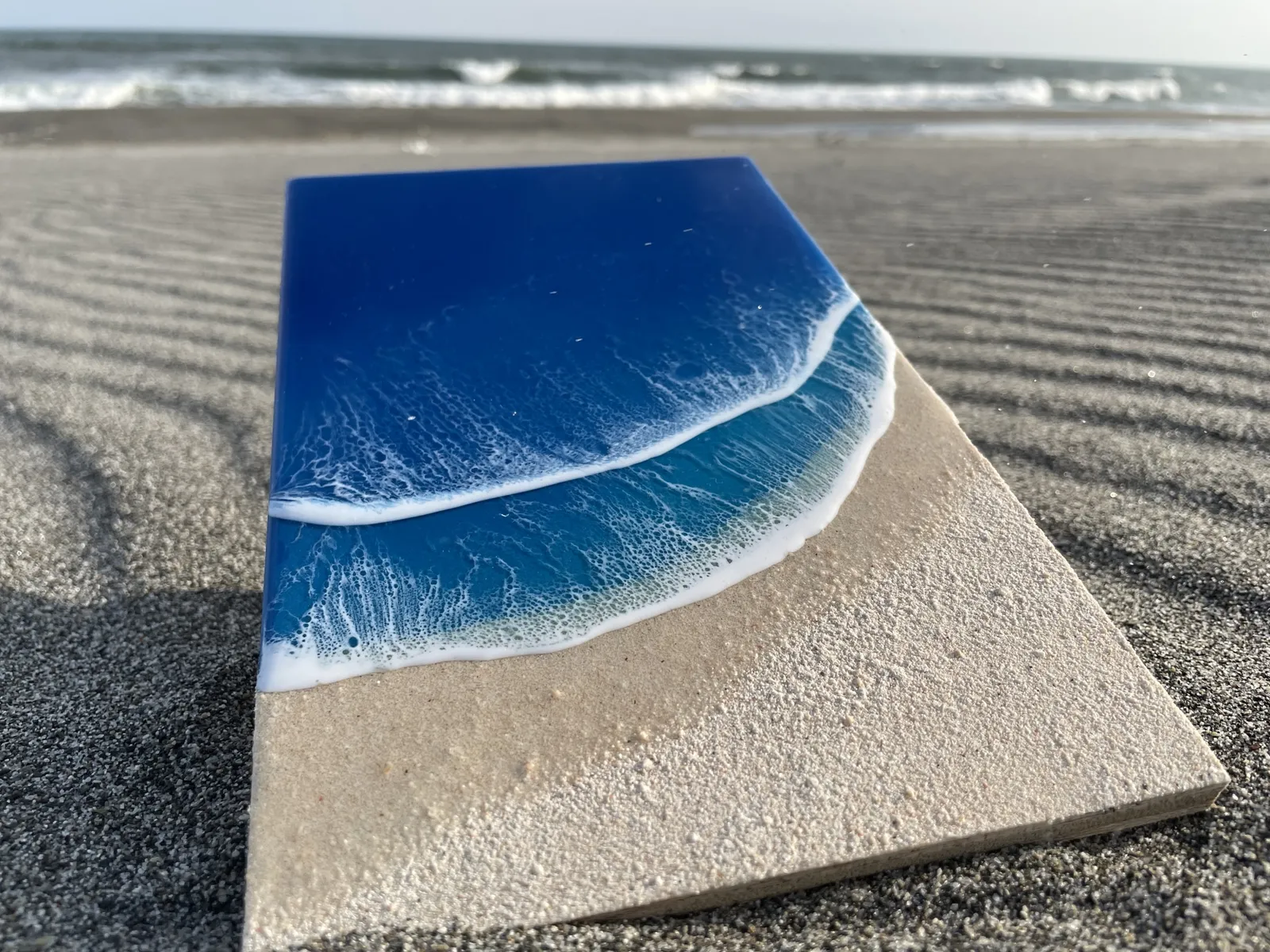 砂浜に置かれた、濃い青の海と白い波を表現したレジンアート