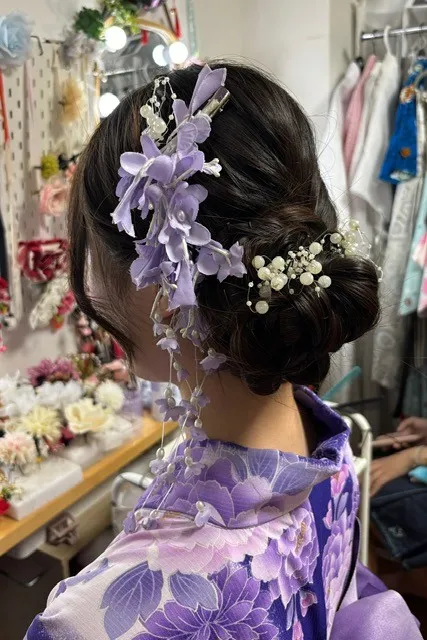 紫の花飾りとパールを付けたまとめ髪と紫の花柄の着物の後ろ姿