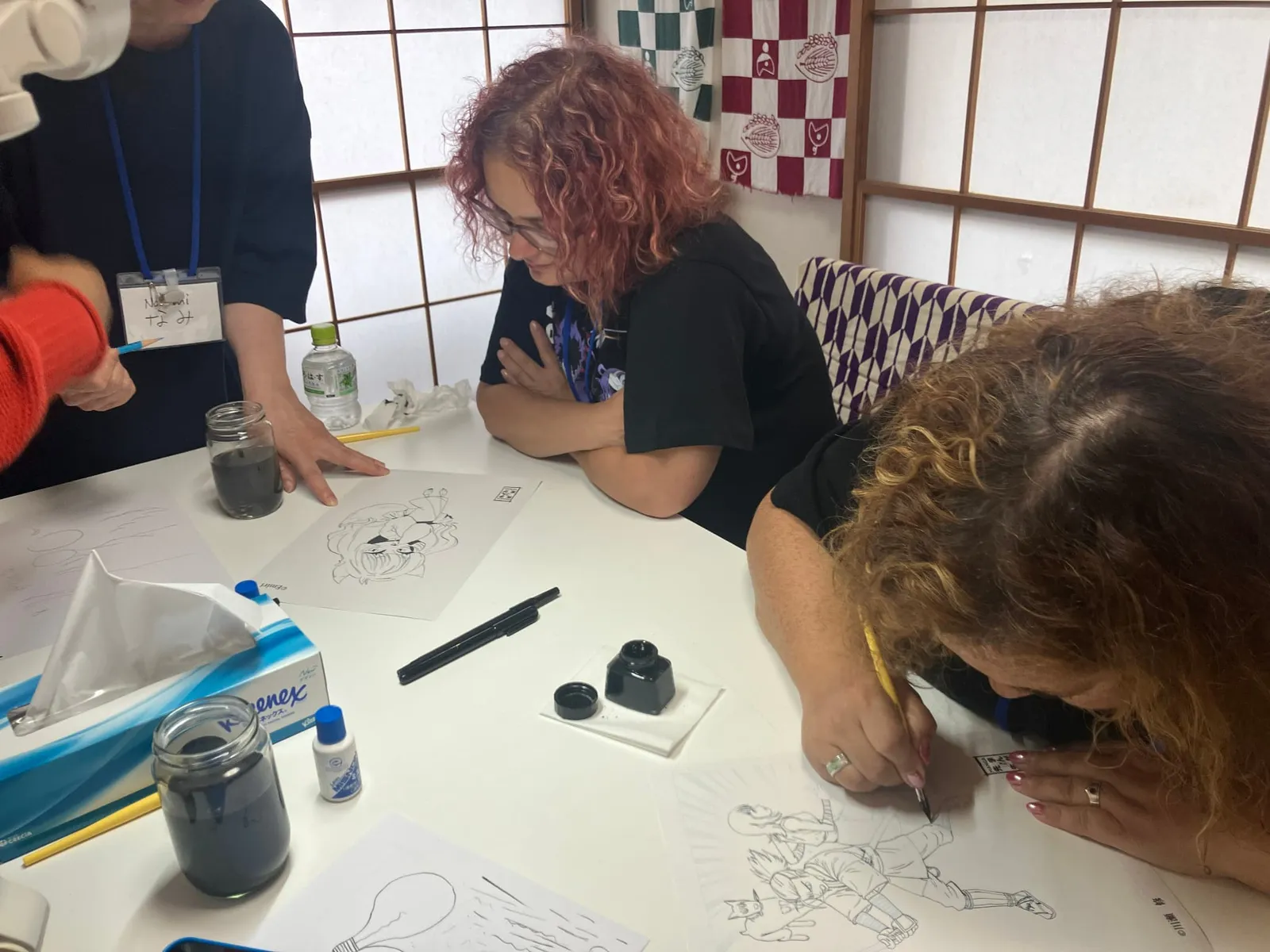 黄色い軸のつけペンで下描きをなぞる手元と雲形定規