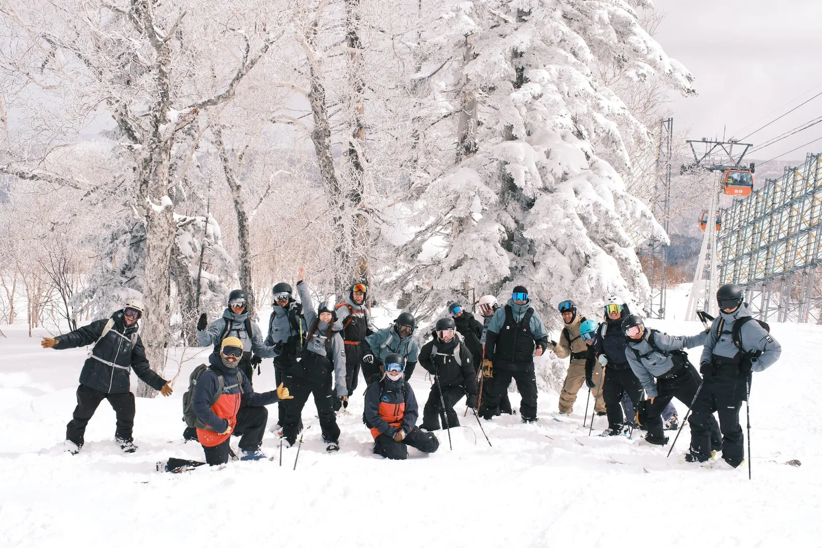 A large group posing against frost-covered trees and gondolas for a group photo