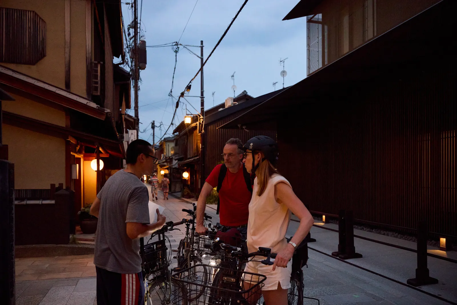 Participants stopping their bikes in a machiya alley to listen to the guide