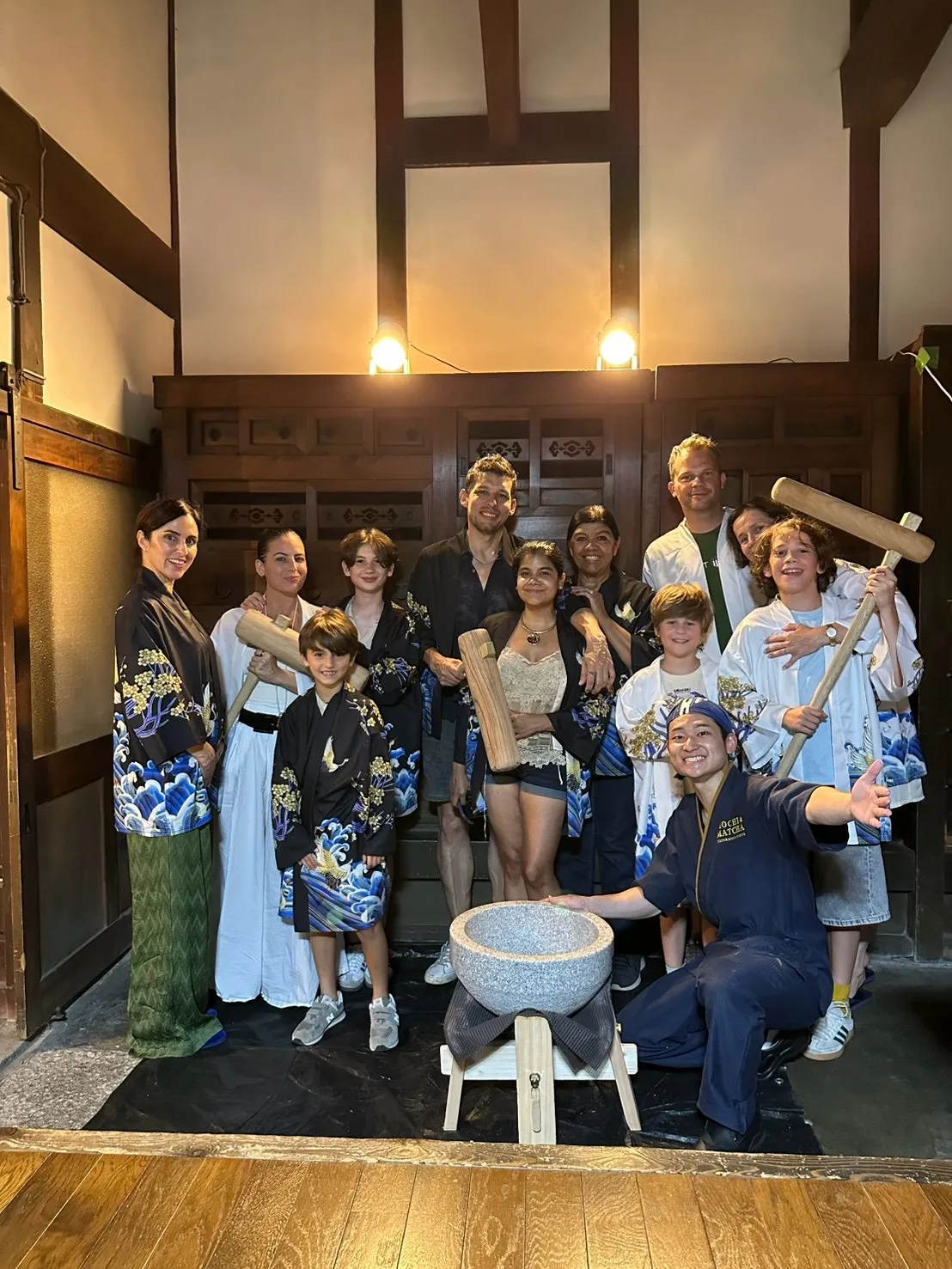 京町家の土間で杵を持った参加者グループとスタッフが記念撮影する様子