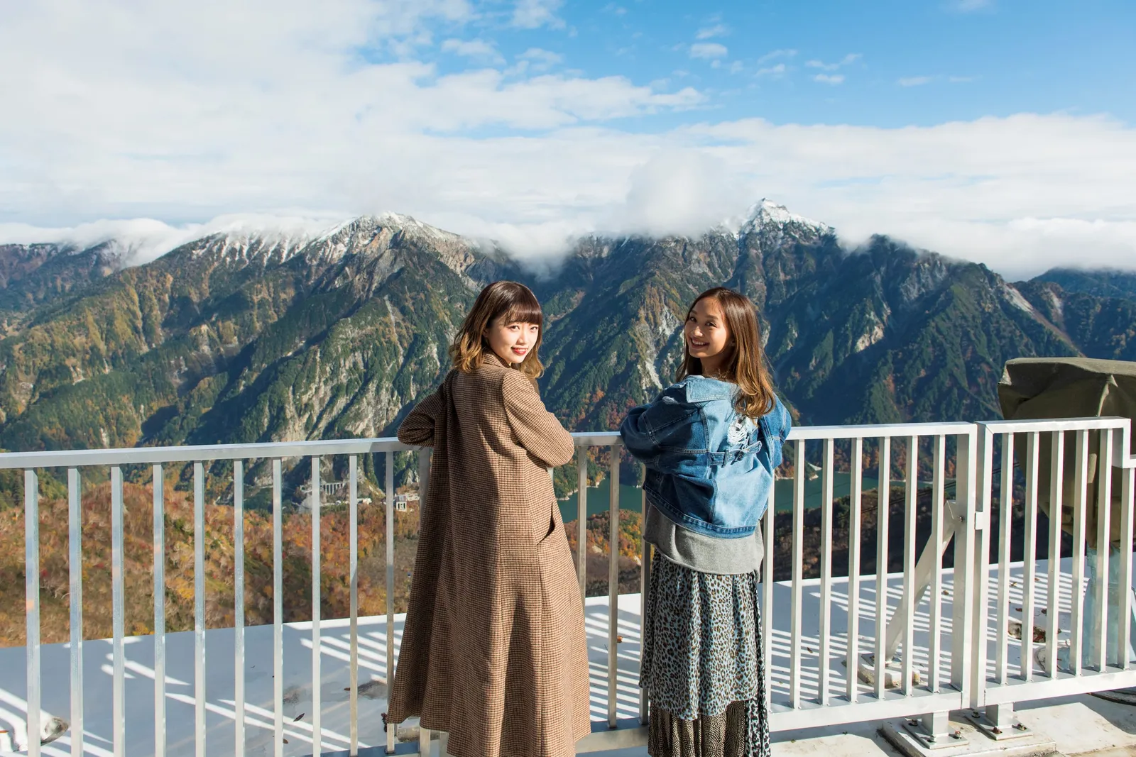 大観峰の展望デッキで山並みを背景に立つ2人の旅行者