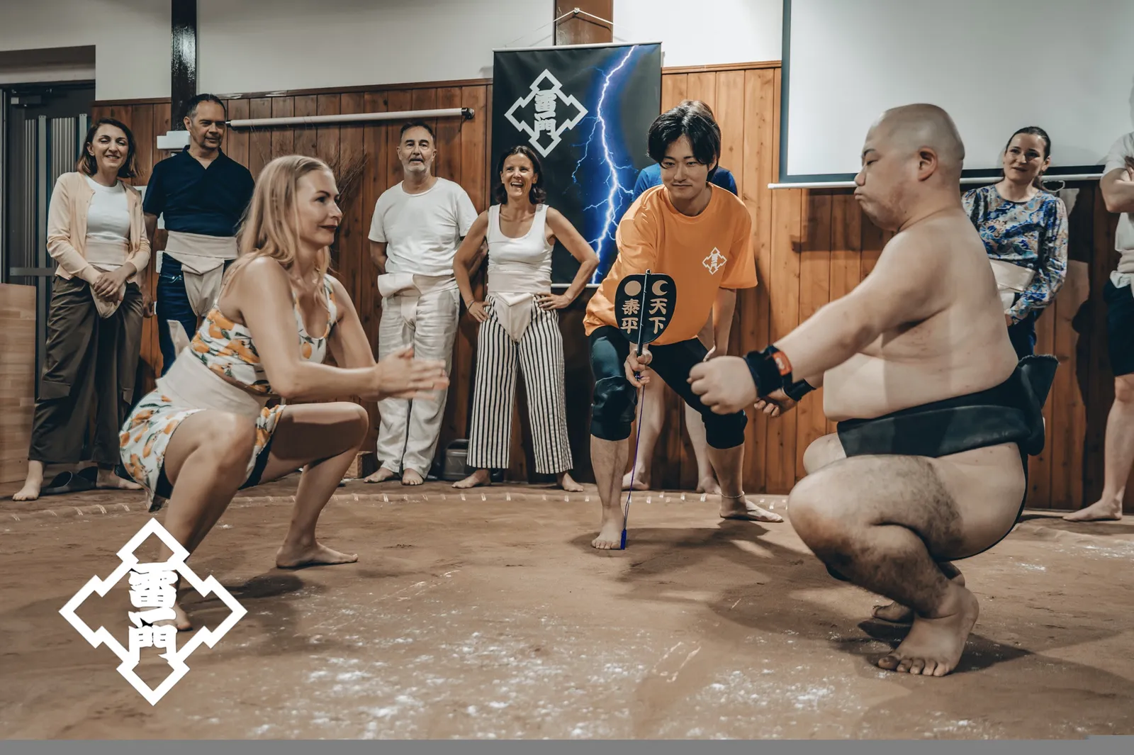 在手持军配的行司面前,女性参加者与力士摆出仕切姿势