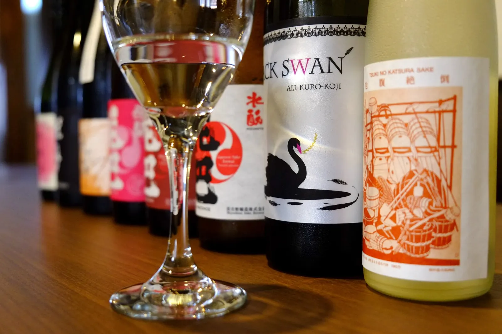 並んだ日本酒ボトルの手前にグラスに注がれた日本酒