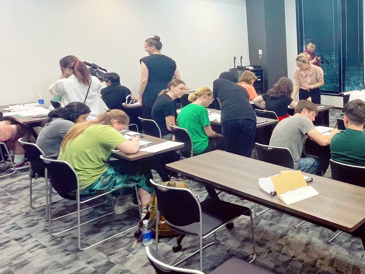 Many participants sitting at desks and drawing in a large, meeting-room-style space