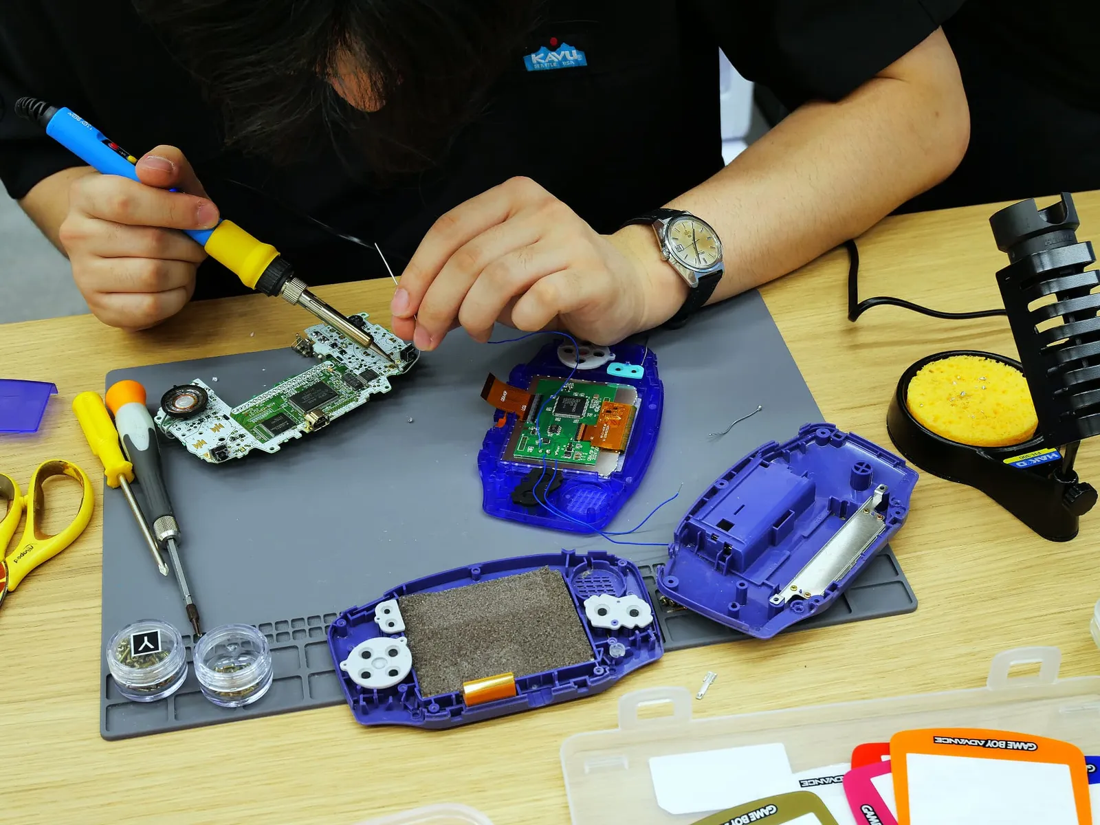紫のシェルとIPS液晶を基板にはんだ付けする手元