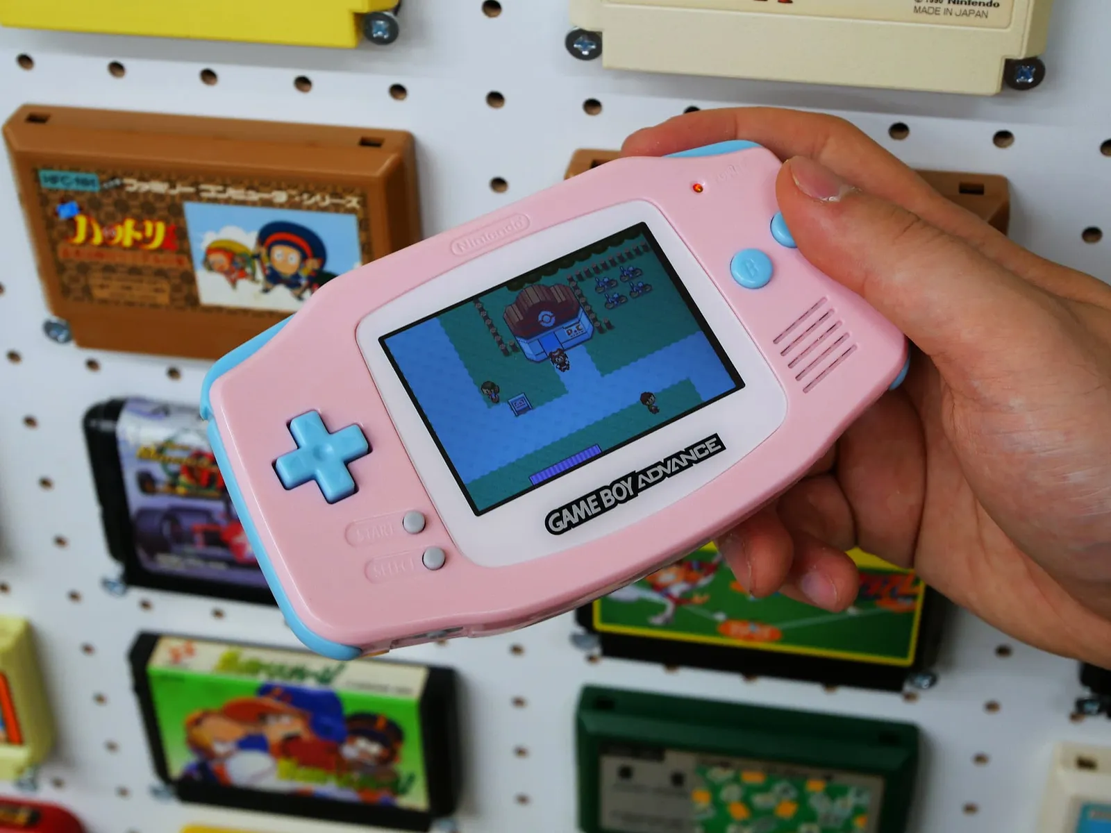 ピンクとブルーのシェルで組んだゲームボーイアドバンスでゲームをプレイする手元