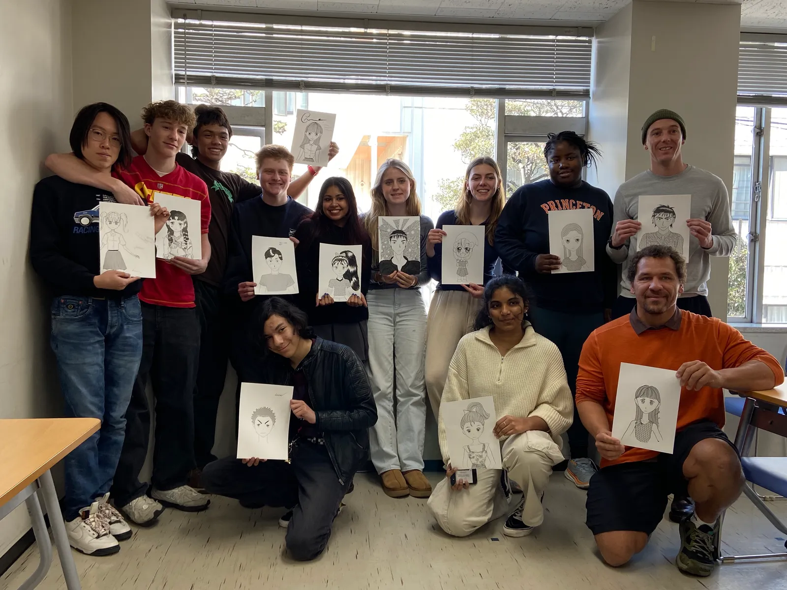 A group photo of many participants holding up the manga illustrations they each drew