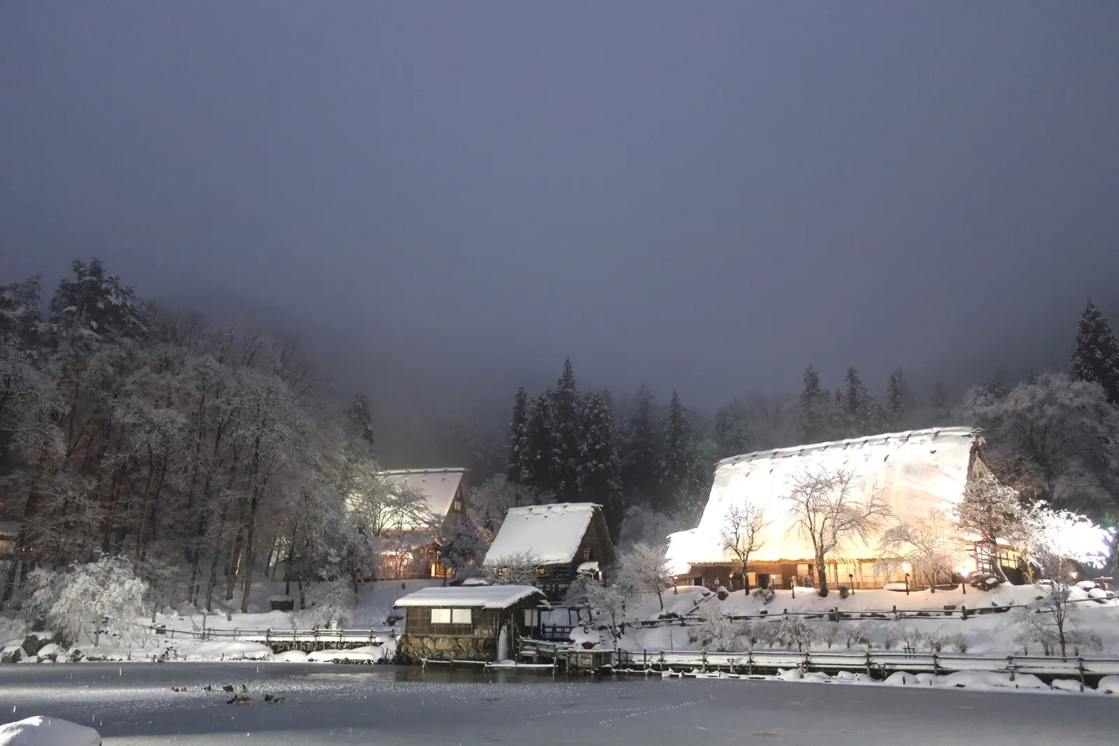 雪景色の中でライトアップされた飛騨の里の民家