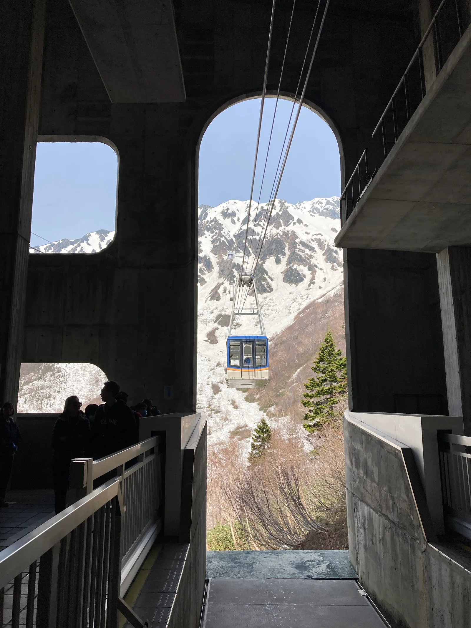 駅のアーチ越しに見える立山ロープウェイのゴンドラと雪山