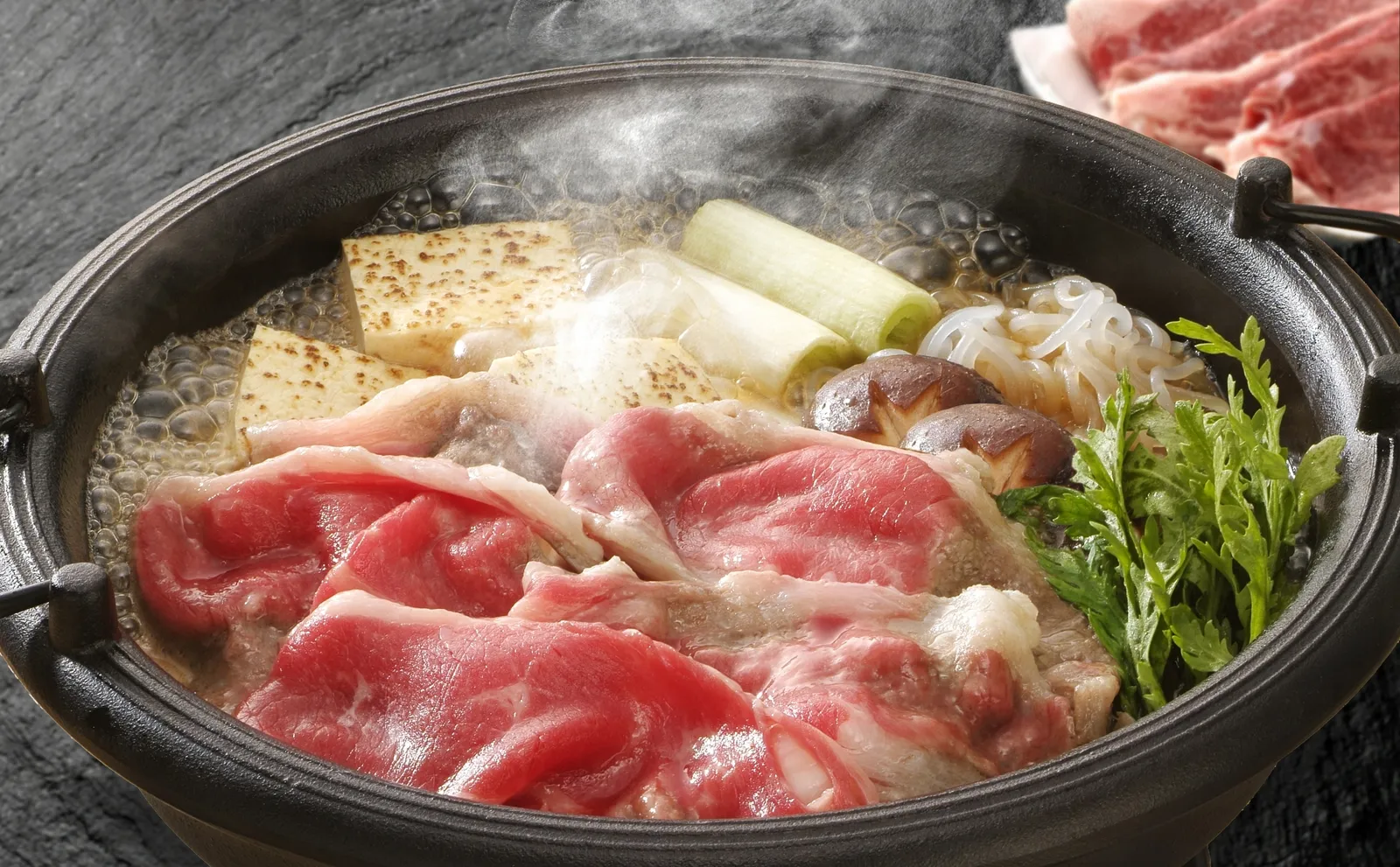 牛肉や豆腐、ねぎを煮込むすき焼き鍋