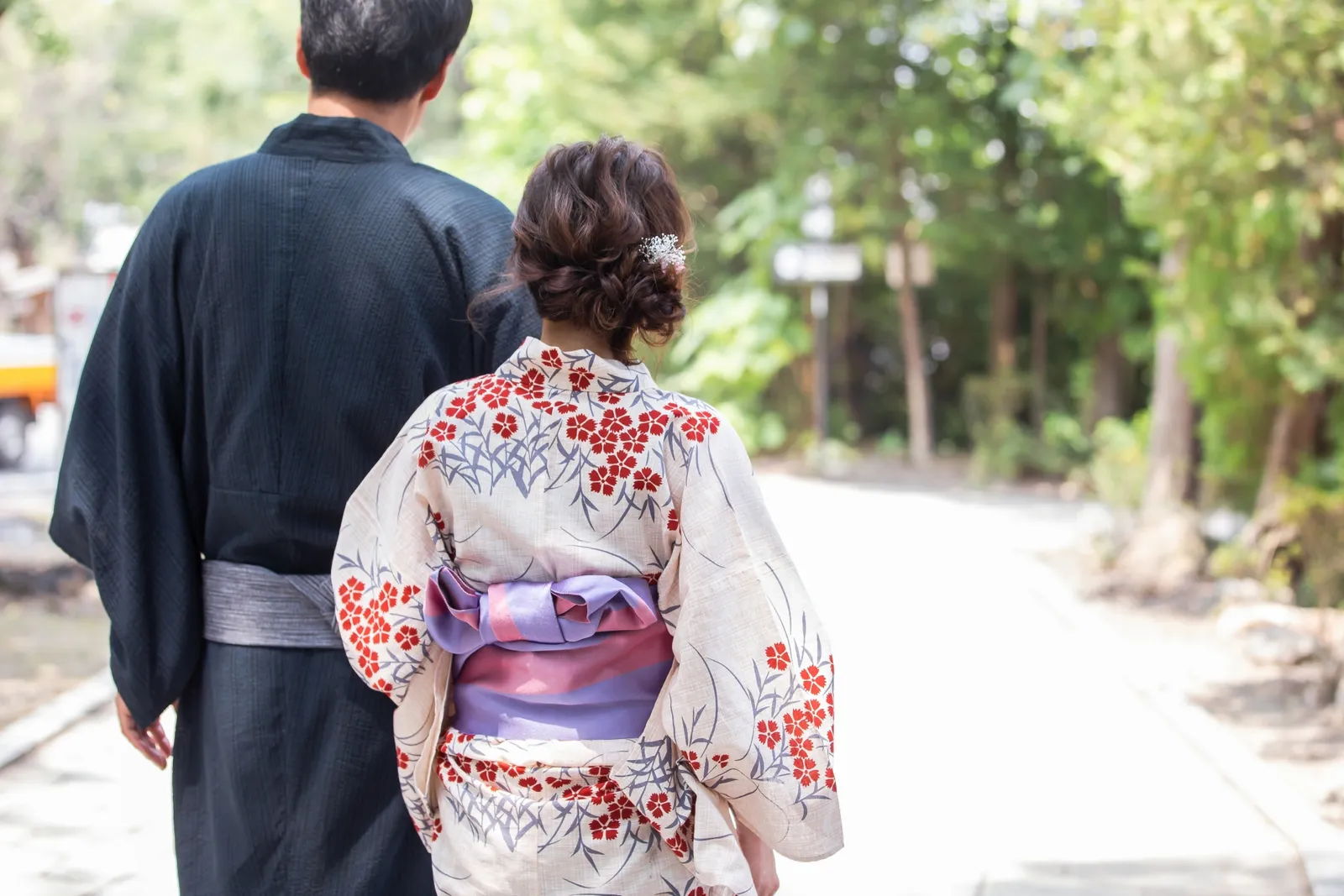浴衣姿で木立の道を歩く2人の後ろ姿