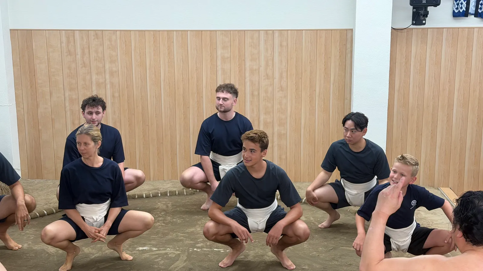 Participants crouching in black t-shirts and mawashi
