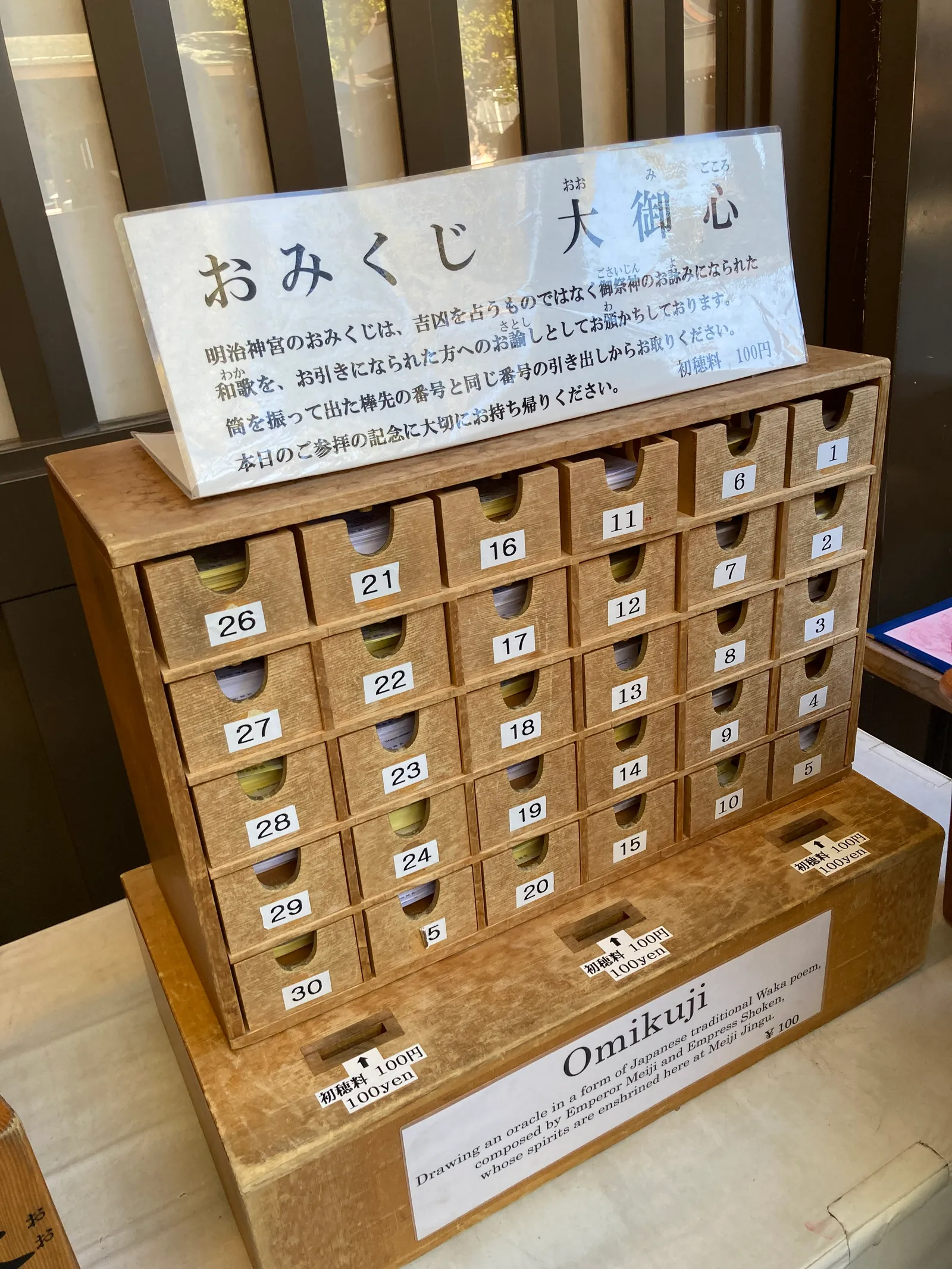 番号の付いた引き出しが並ぶおみくじの木箱と説明板