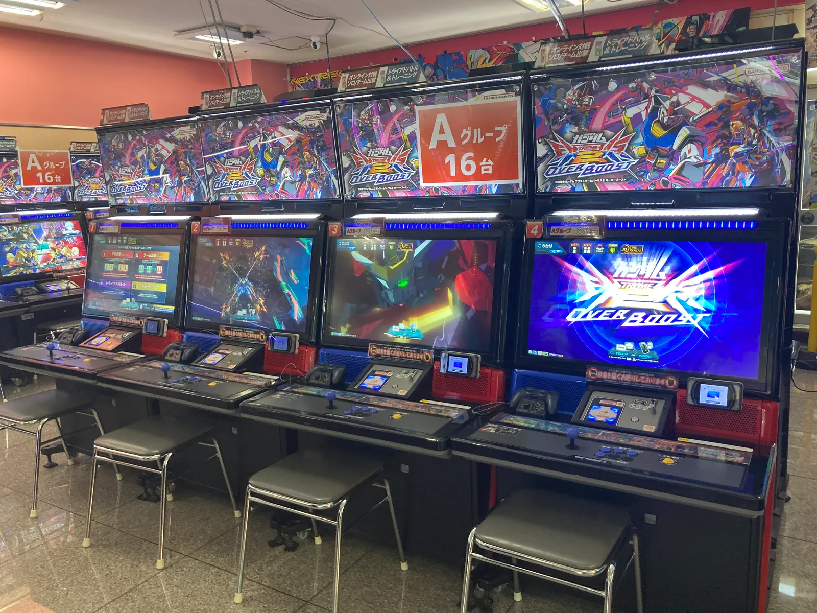 ガンダムの対戦アーケード筐体が横一列に並ぶゲームセンター内
