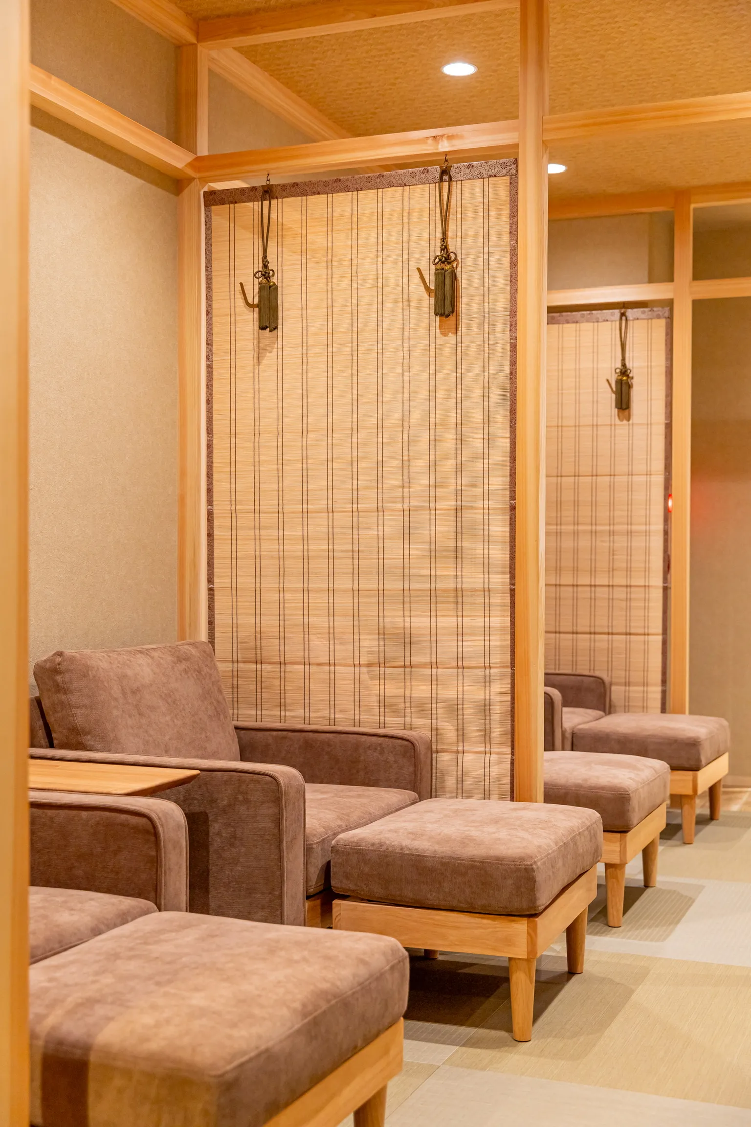 Sofas and ottomans lined up in a space divided by sudare screens