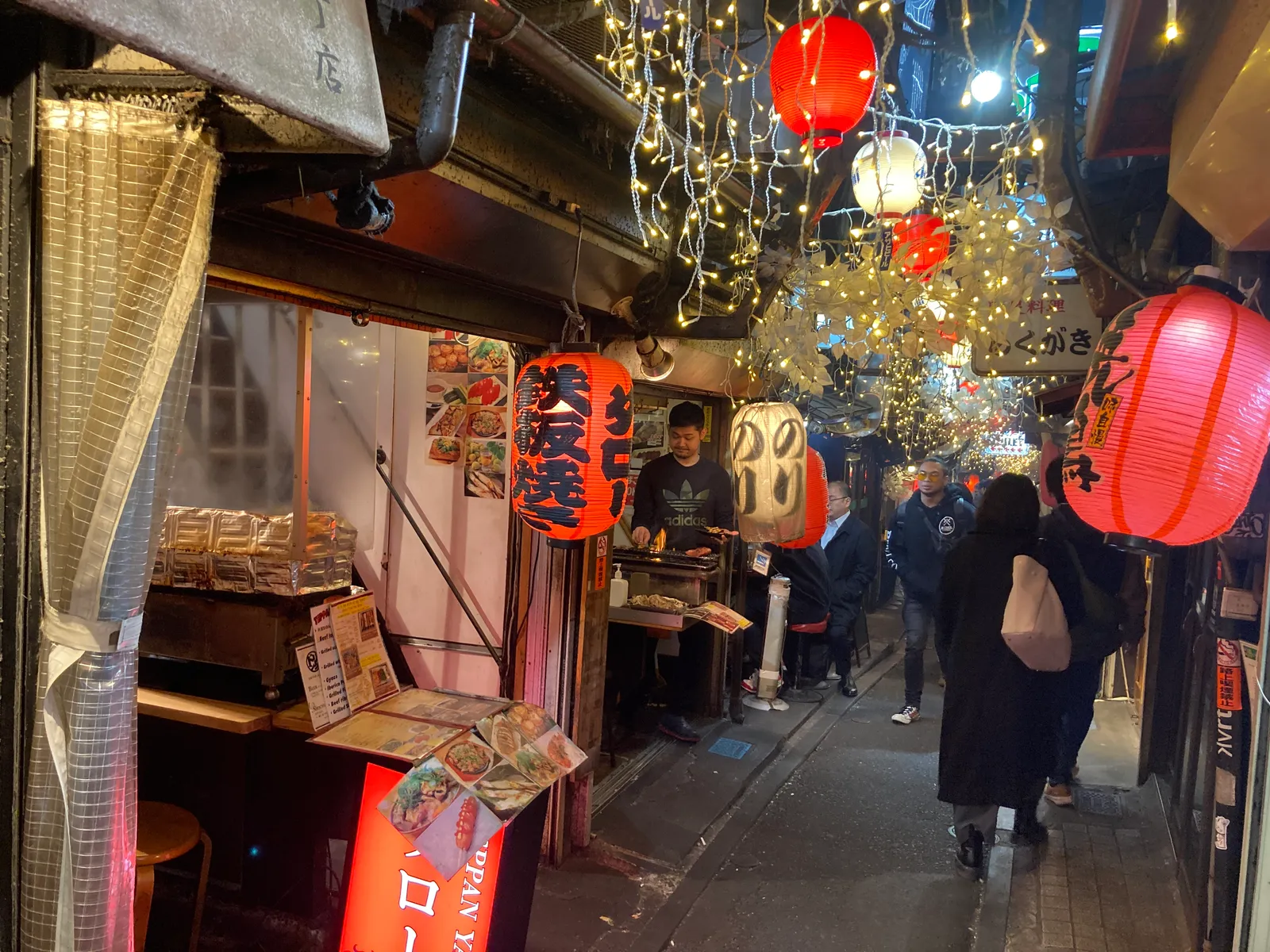 夜の細い路地に小さなバーの看板が並ぶゴールデン街