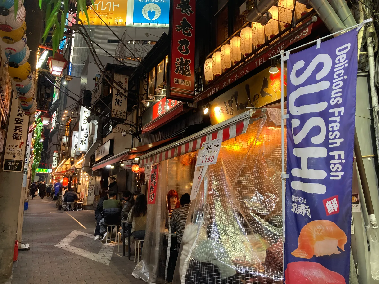 寿司の幟や居酒屋の看板が並ぶ横丁の通り