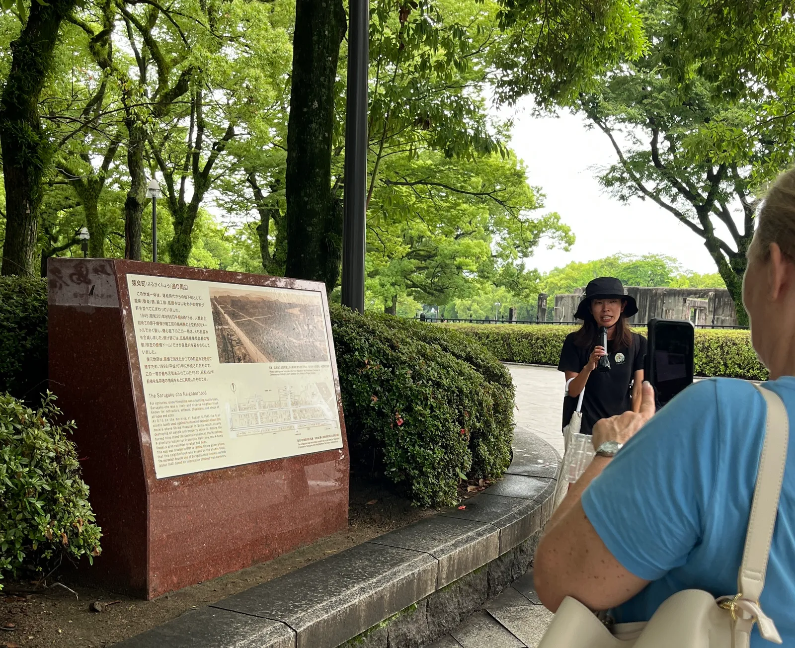 猿楽町の街並みを紹介する案内板の前で説明するガイド