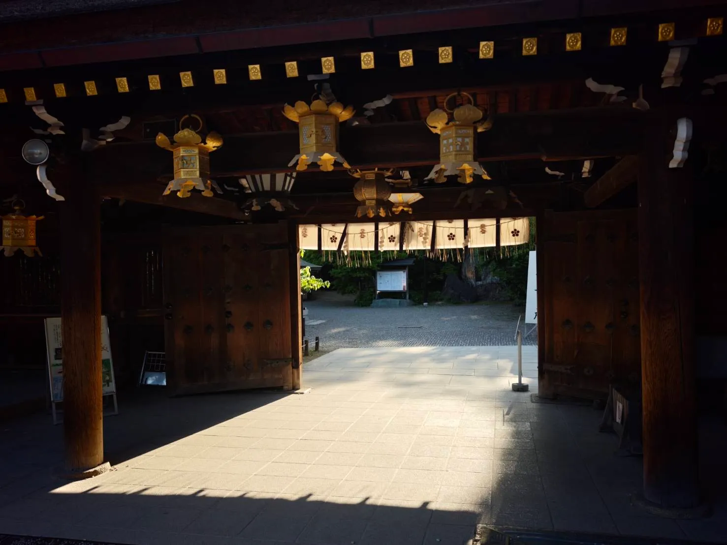 金色の吊り灯籠が下がる神社の門と木の扉