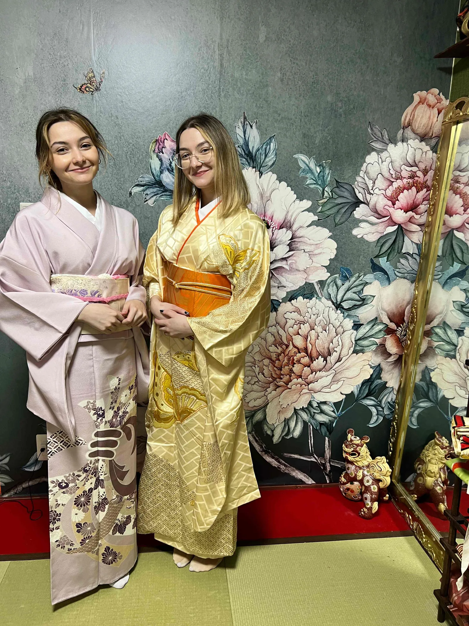 花柄の壁と金縁の鏡の前で着物を着た2人が並ぶ