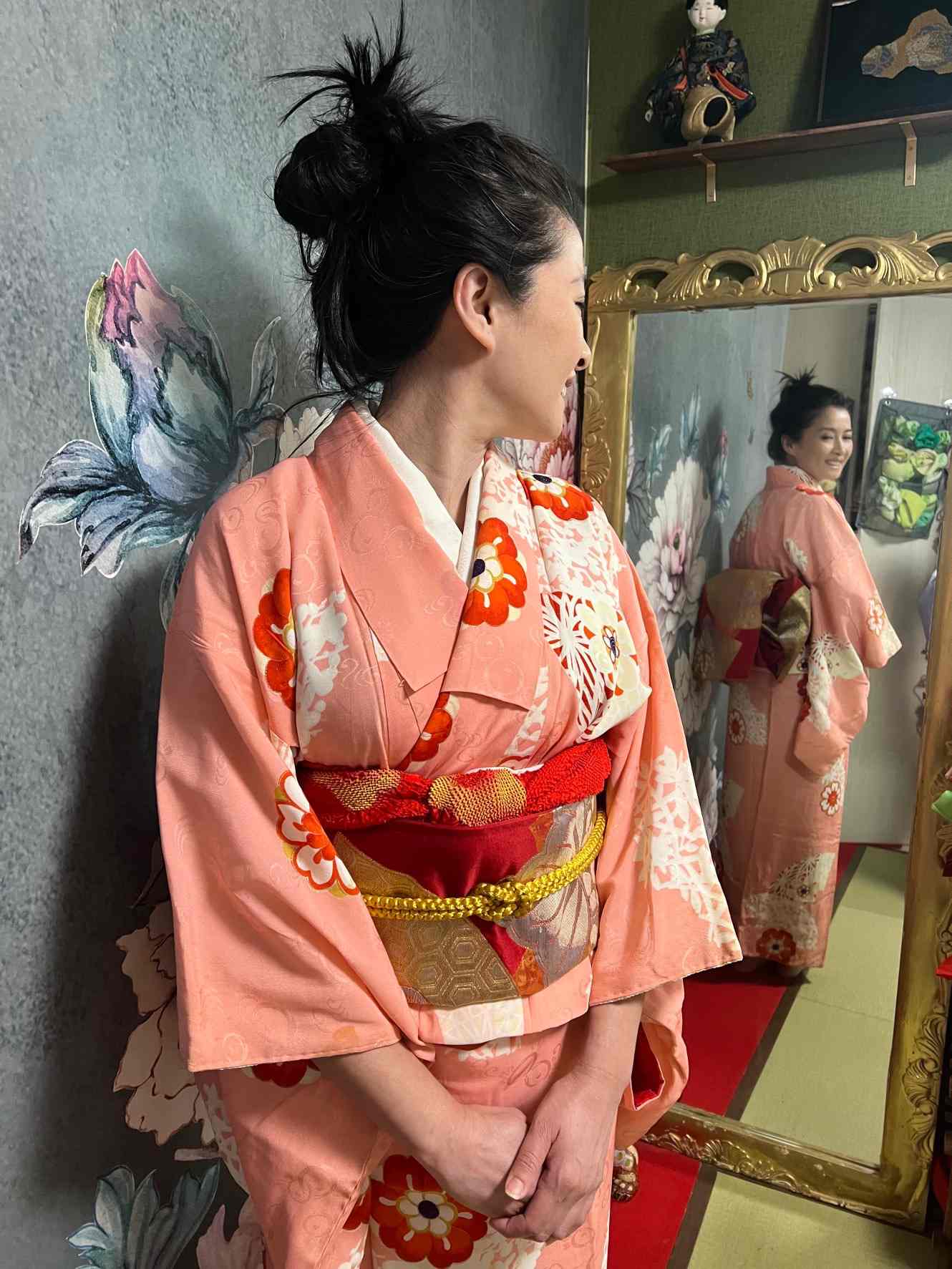 鏡の前で帯を締めた着物姿を横から写した様子