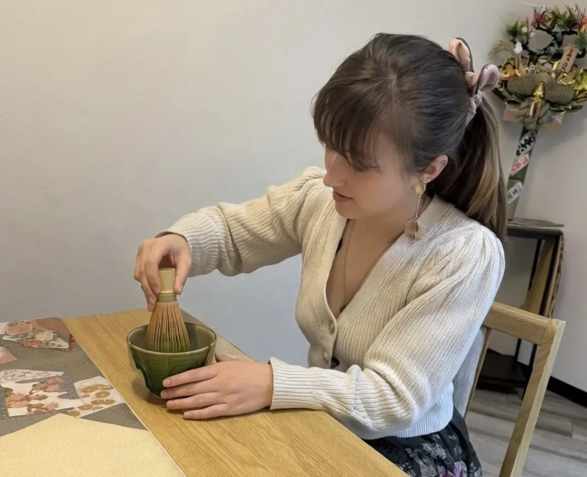茶碗の中で茶筅を使い抹茶を点てる女性